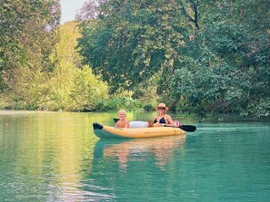 Un kayak sur une étendue d’eau calme, avec une végétation luxuriante en arrière-plan.