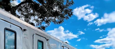 A row of mobile homes with external shower facilities, metal stairs, and a dirt ground.