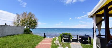 A pathway leading to a seaside view with a gazebo, seating area, and a view of the sea.