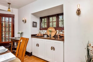 A kitchen with white cabinets, copper cookware, and a wooden barrel.