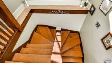Una escalera de madera con barandilla, paredes blancas y cuadros enmarcados.