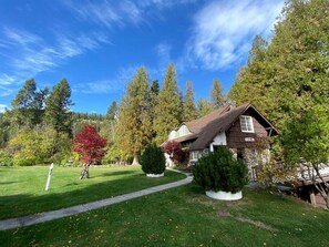 A house with a well-maintained lawn, a pathway leading to the entrance, and a variety of trees surrounding the property.