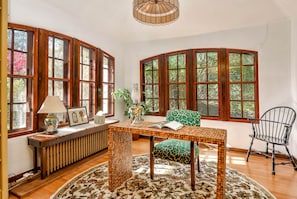 A room with large windows, a wooden table, a bench, a chair, and a radiator.