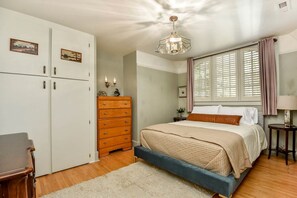 A bedroom with a bed, dresser, wardrobe, and a chandelier. - Elegance by the River: Classic Rental with Scenic Views in Metaline Falls, WA (Metaline Falls)