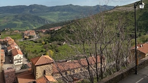 A mountainous landscape with a village, stone buildings, and a clear sky. - Oasis aloe vera (Troina)
