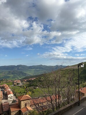 A mountainous landscape with a village, stone buildings, and a clear sky.