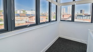 A room with large windows, a black carpet, and a view of buildings. - Rickman Apartment (Birmingham)