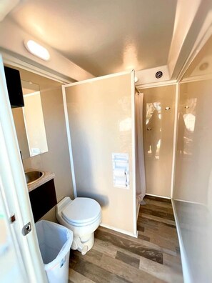 A compact bathroom with a toilet, sink, and mirror.