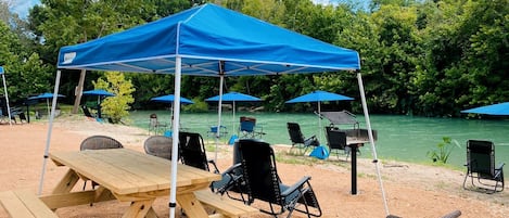 A picnic setup with a table, chairs, and a blue canopy.