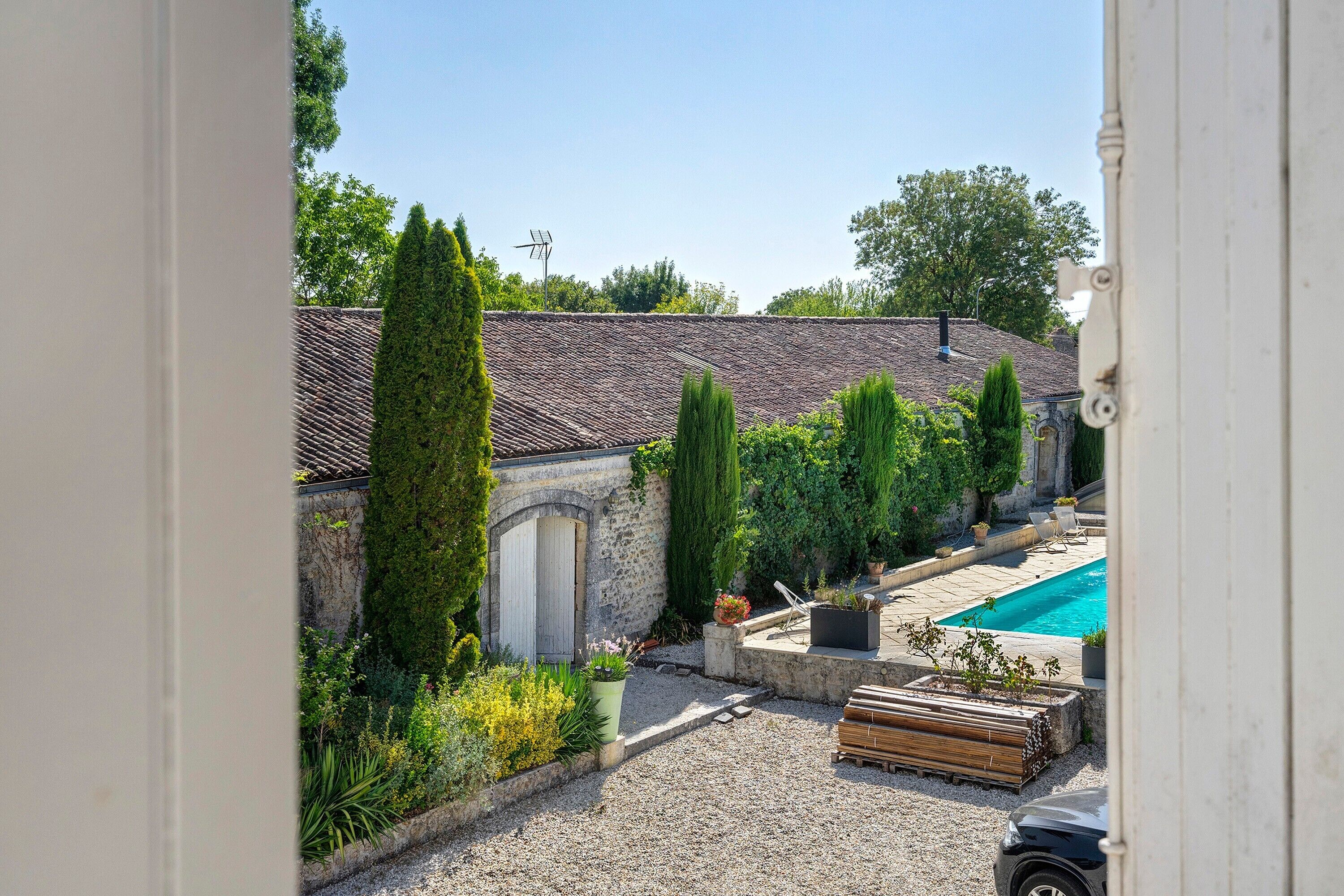 Une cour avec une piscine, un mur en pierre et une grande variété de plantes.