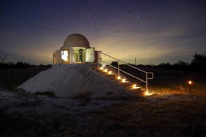 A dome-shaped observatory with a staircase leading up to it, surrounded by a gravel area.