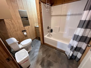 A bathroom with a toilet, a bathtub, and a shower curtain.
