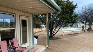 Ein Gebäude mit überdachter Veranda, Sitzgelegenheiten im Freien und einer Bank.
