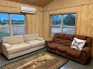 A room with two sofas, a rug, and large windows.