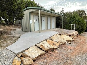 A building with a covered entrance, a concrete ramp, and a stone wall.