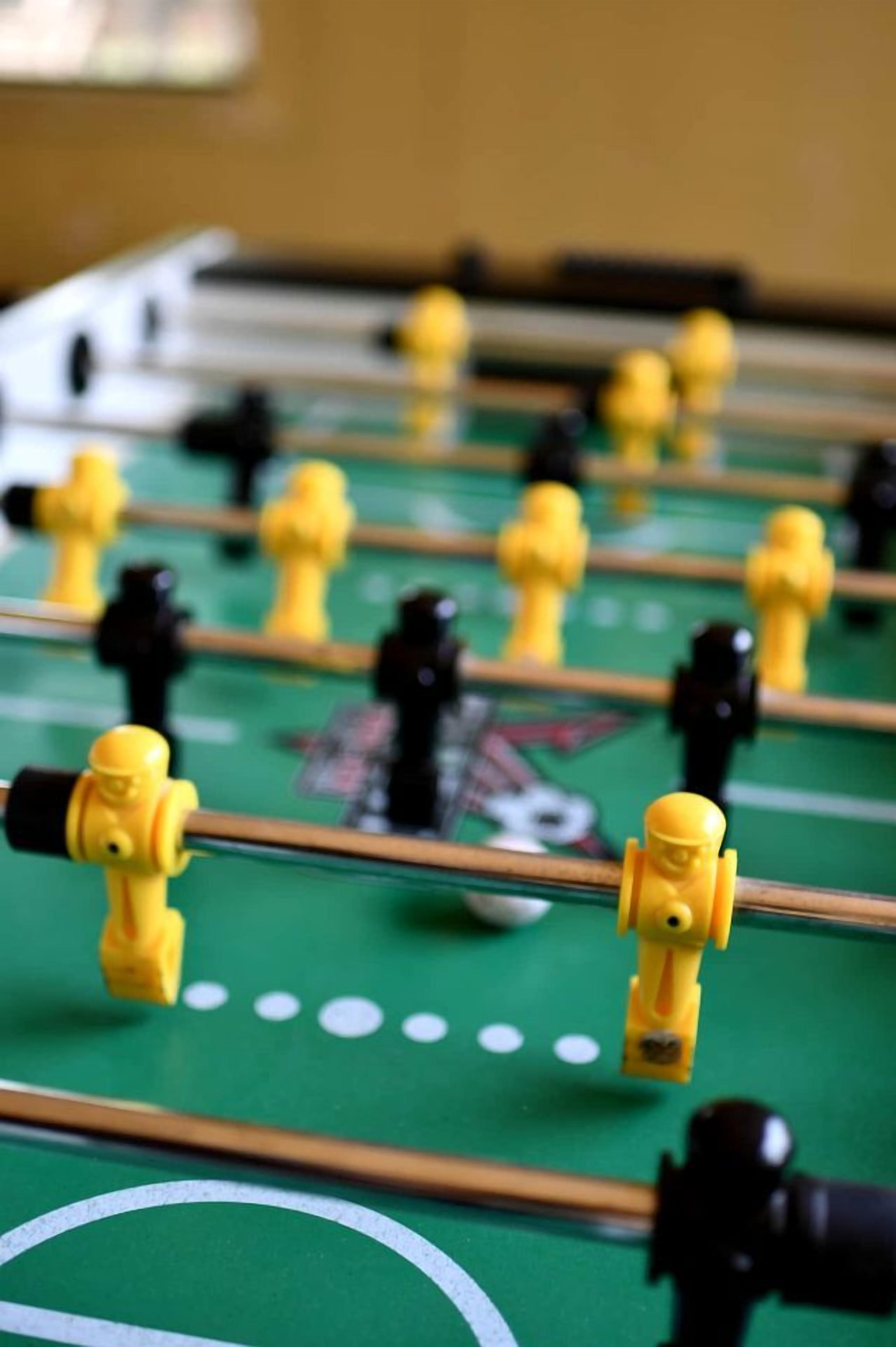 A close-up of a foosball table with yellow and black figures.