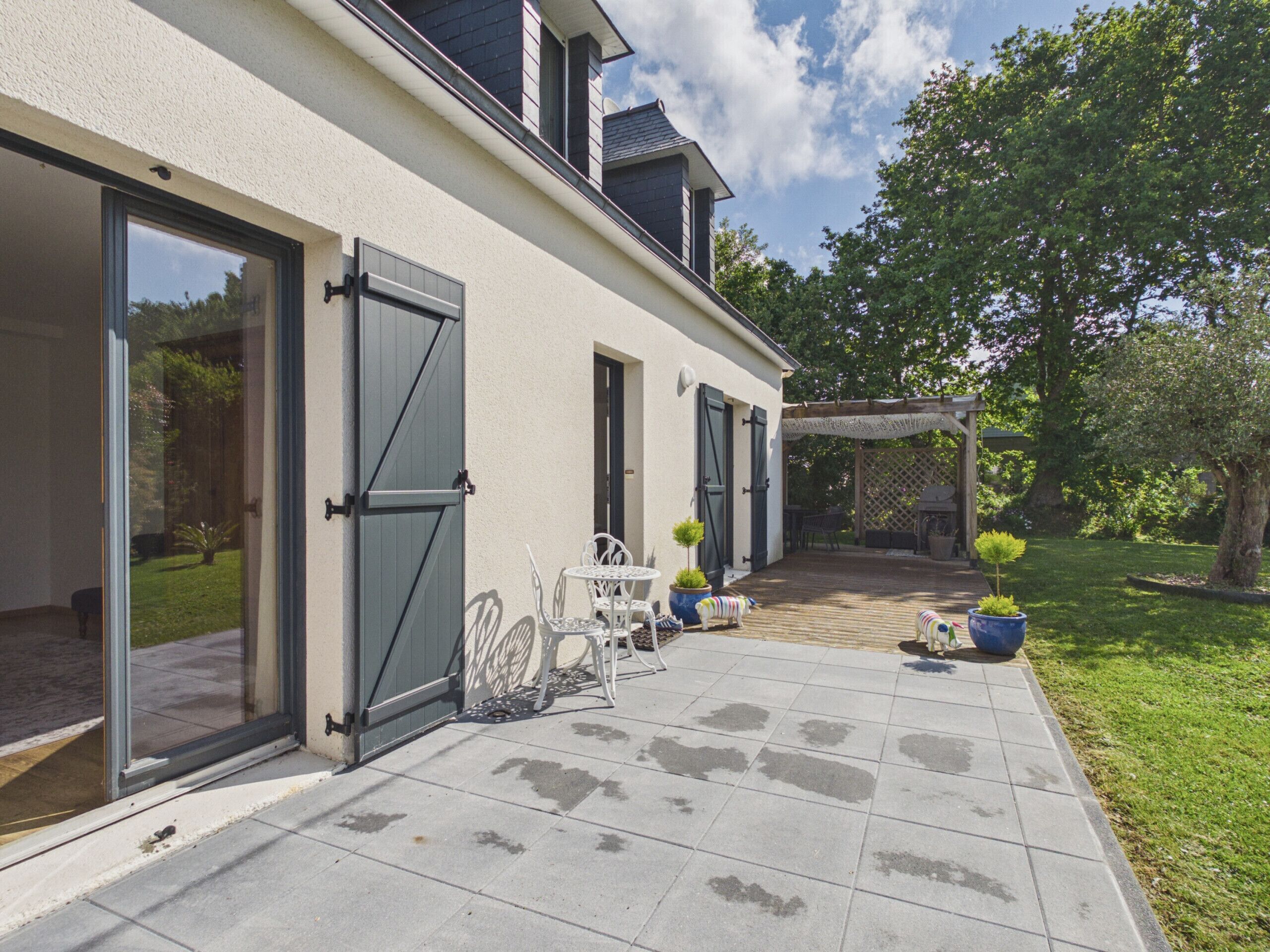 Une maison avec un patio, des portes coulissantes et un jardin.