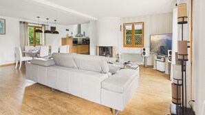 A modern living room with a sofa, dining area, kitchen, and a fireplace. - House for 8 with bbq, big garden and terrace (Fouesnant)