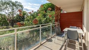 Ein Balkon mit Glasgeländer, einem Tisch und zwei Stühlen.