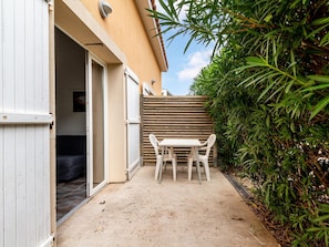 A patio with a table and chairs, a sliding door, and a wooden fence. - Charming House Stay in Saint-cyprien (Saint-Cyprien)
