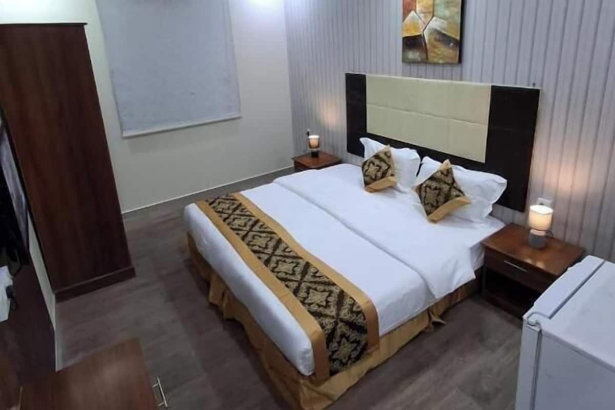 A hotel room with a bed, bedside tables, a wall-mounted artwork, and a ceiling light.