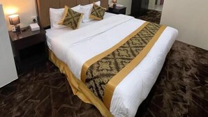Habitació d'hotel amb un llit gran, una tauleta de nit amb una làmpada, un aparell d'aire condicionat i un quadre a la paret.