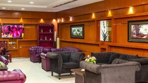 Rebedor d'hotel amb sofàs de pell, una televisió, obres d'art emmarcades i una estant decorativa vermella.