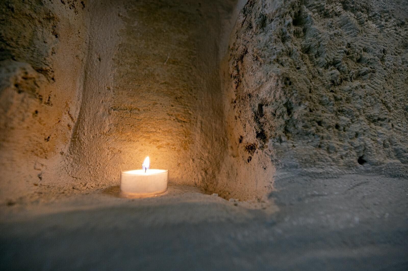A candle in a narrow, textured alcove.