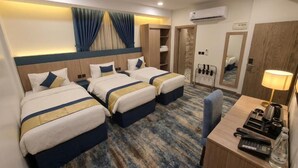 A hotel room with two beds, a desk with a lamp, a phone, and a minibar. - Alhijrah View 2 Hotel (Makkah)
