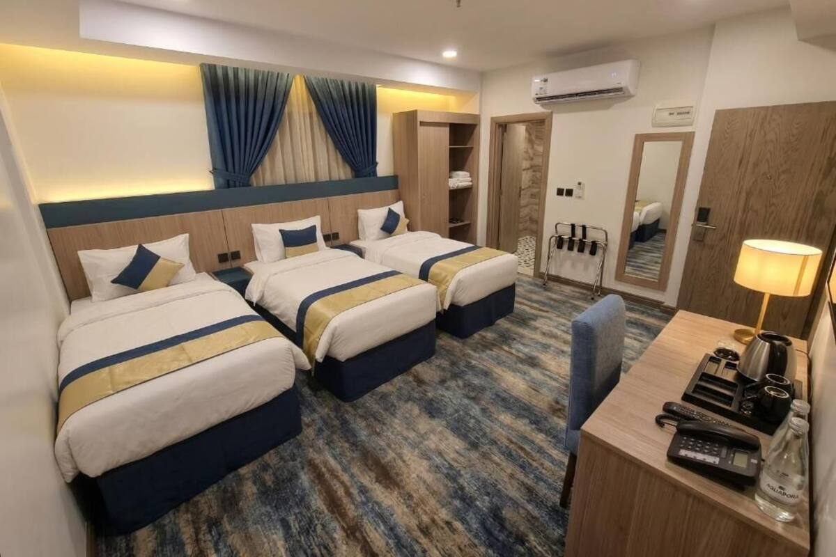 A hotel room with two beds, a desk with a lamp, a phone, and a minibar.