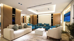 A modern living room with a sofa, armchairs, a coffee table, and a television. - Alhijrah View 2 Hotel (Makkah)