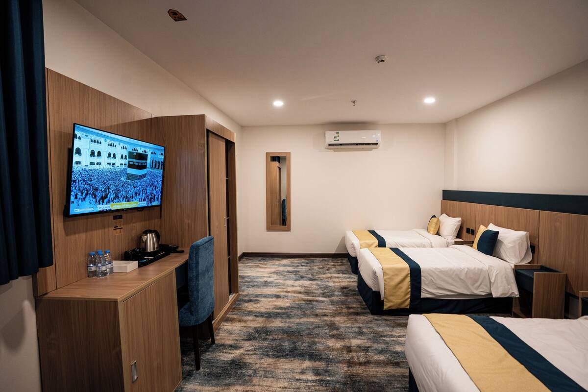 A hotel room with a TV, two beds, a desk, and a wardrobe.