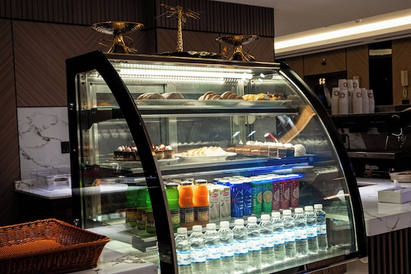 Una vitrina de panadería con diversos productos horneados y una selección de agua embotellada.