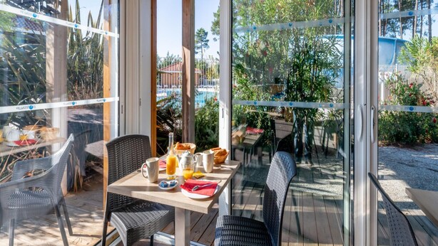 A dining area with a table set for breakfast, including a bottle, jug, and plates. - Nature Stay Near Biscarrosse Lake (Parentis-en-Born)