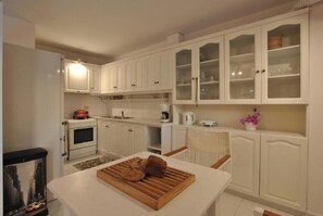 Eine Küche mit weißen Schränken, einem Holztisch mit Brot und einem Aquarium.