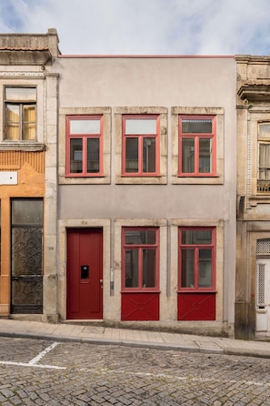 Ein Gebäude mit roter Tür und Fenstern, mit den Hausnummern 154 und 156, vor einer Kopfsteinpflasterstraße.