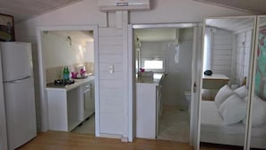 Ein Zimmer mit einem Bett, einer kleinen Küchenzeile und einem Badezimmer.