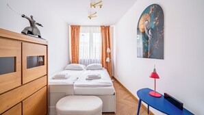 Un dormitori amb un llit, un taulell de fusta, una taula petita amb una làmpada i una obra d'art penjada a la paret.
