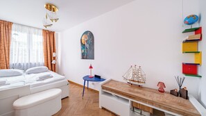 Ett välordnat hotellrum med en säng, ett nattduksbord, ett skrivbord och en liten bokhylla.