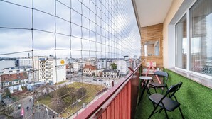Un balcó amb vista a un paisatge urbà, una petita zona d'estar amb cadires, i una finestra que donava al carrer.