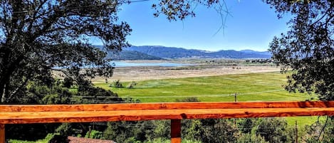 Un banco de madera con vistas a un paisaje pintoresco, con una vista despejada de colinas lejanas y una masa de agua.