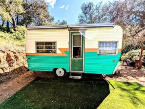 Una caravana clásica con puerta, ventanas y un escalón pequeño que lleva a la entrada.