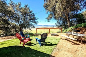 Un patio al aire libre con mesa y sillas, un pozo de fuego y vistas del paisaje.