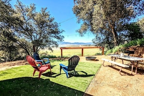 Eine Terrasse im Freien mit Tisch, Stühlen, einem Feuerkorb und Blick auf die Landschaft.