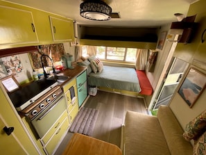 Ein kompaktes Wohnmobil-Interieur mit Kochnische, Bett und einer kleinen Sitzecke.