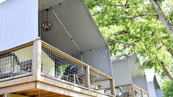 A multi-level building with balconies, a covered outdoor area, and a tree in the background.