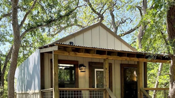 A wooden cabin with a porch, a staircase, and a window. - Waterfront Safari Cabin San Antonio, Texas (Marion)