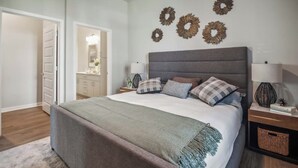 Un dormitorio con una cama grande, una mesita de noche, una lámpara y decoración en la pared.