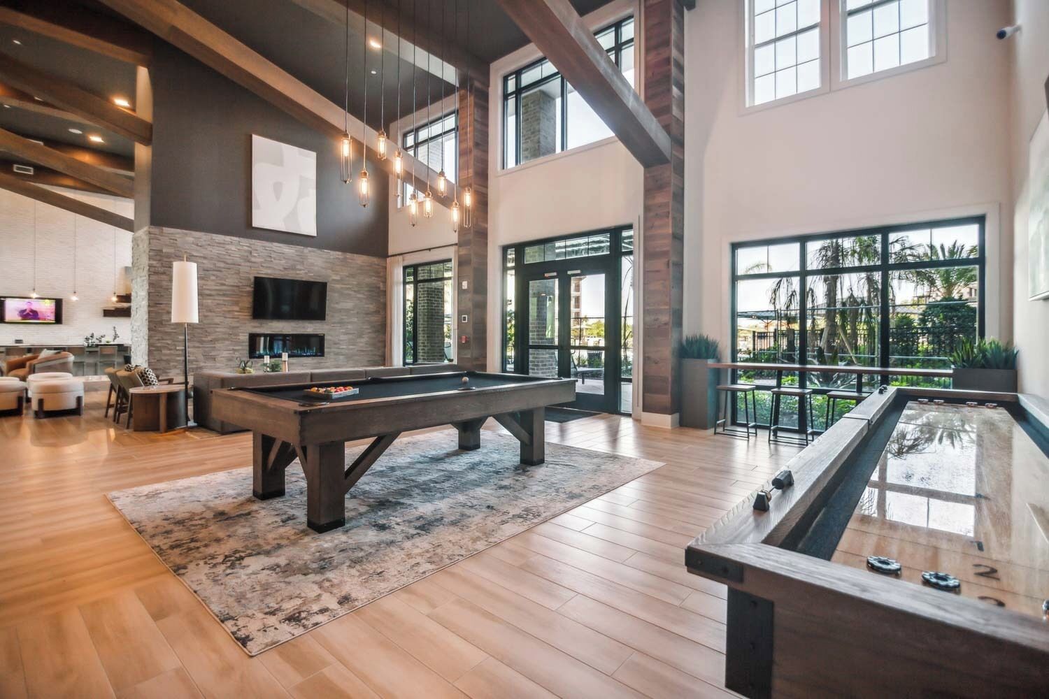 A spacious indoor area with a pool table, a billiards table, and a seating area with a flat-screen TV.