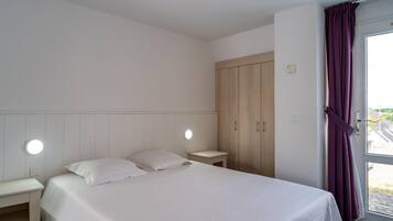A bedroom with a bed, bedside tables, a wardrobe, and a window with curtains.